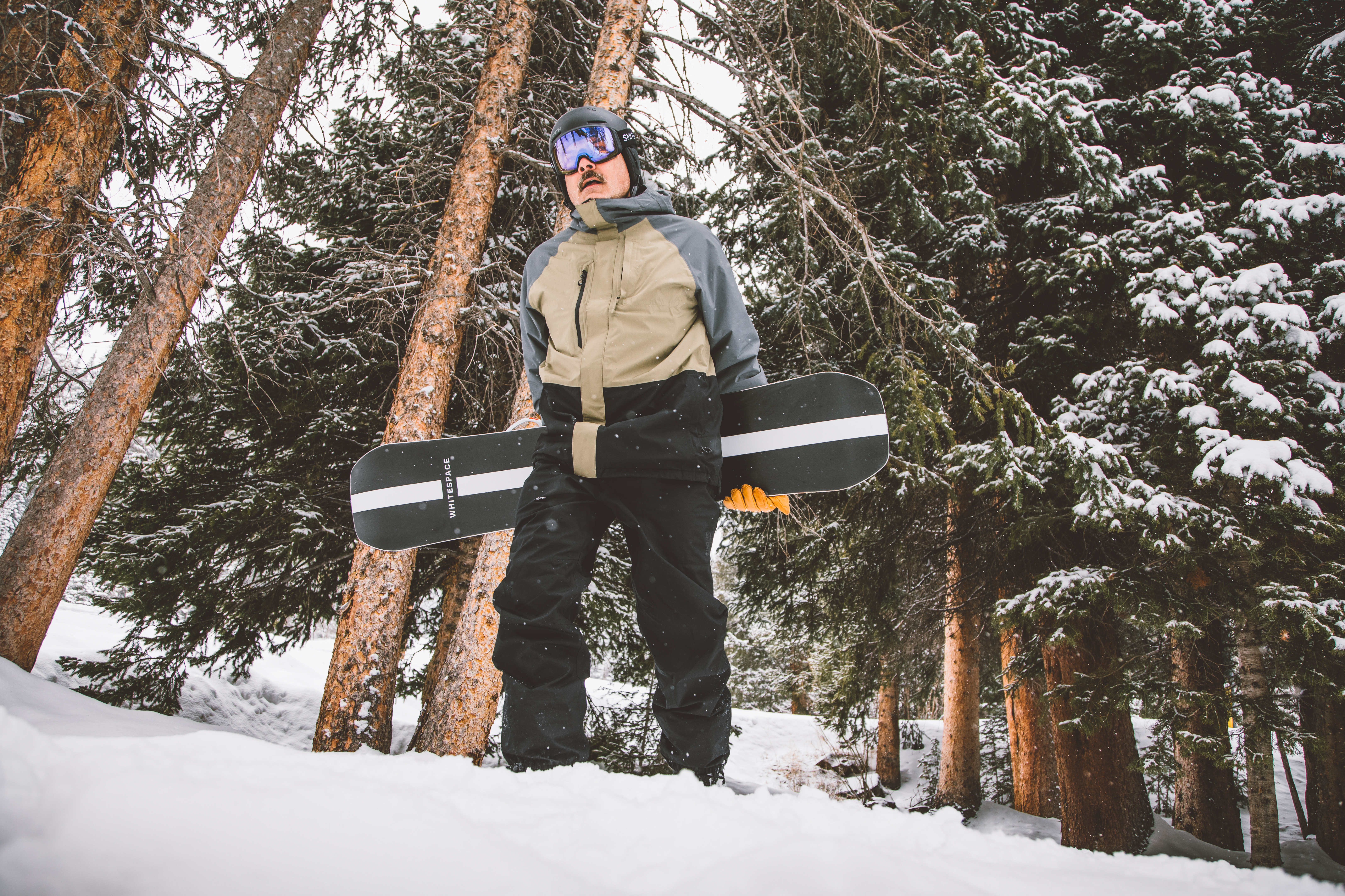 Man holding a snowboard he rented from Sun & Ski Sports